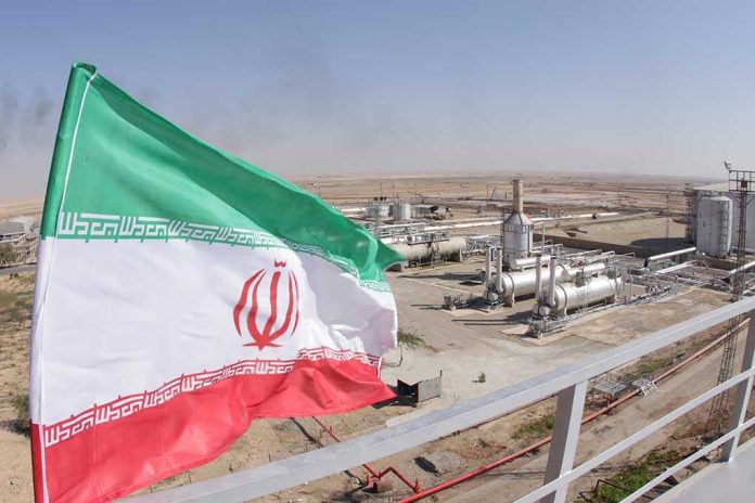 1227310843 Iranian flag near an industrial gas refinery.