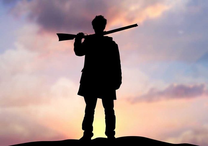 Silhouette of a person holding a rifle against a colorful sunset sky