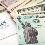 Americans To Get HUGE Tax Refunds A tax refund check from the IRS alongside various denominations of cash