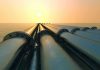 Oil Control Sparks Outrage Industrial pipes extending towards the horizon over water during sunset