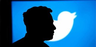 Silhouette of person against blue Twitter logo background.