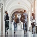 Federal Pressure Forces Elite University’s Hand Four students walking in a corridor together.
